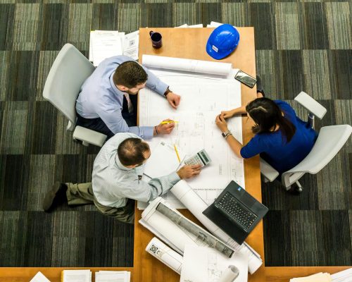 Top view of a team working on construction plans in an office setting.